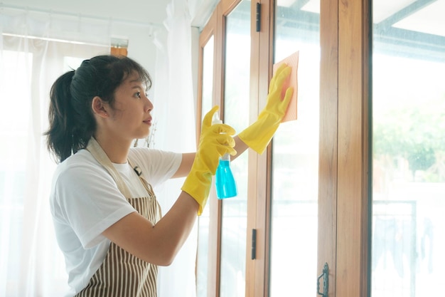 Junge asiatische Frau, die Fenster putzt