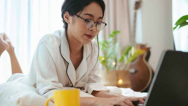 Junge asiatische Frau, die freiberuflich arbeitet, arbeitet zu Hause am Laptop und arbeitet von zu Hause aus