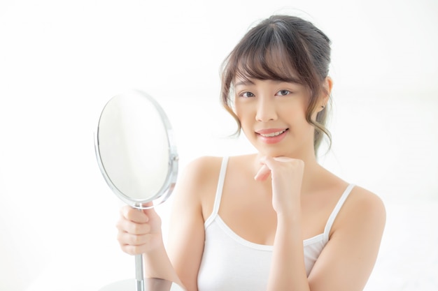 Junge asiatische Frau, die in den Spiegel schaut