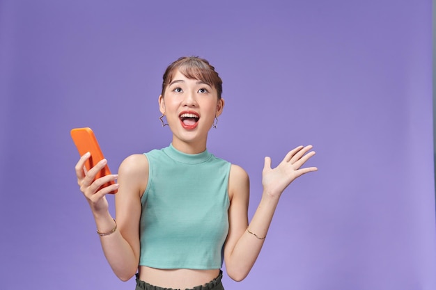 Foto junge asiatische frau, die in der hand telefon mit überraschtem blick hält