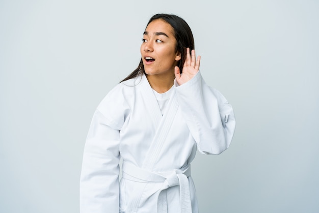 Junge asiatische Frau, die Karate lokalisiert auf weißer Wand versucht, einen Klatsch zu hören.