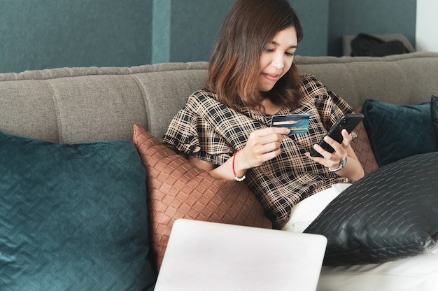 Foto junge asiatische frau, die kreditkarte für online-einkauf verwendet