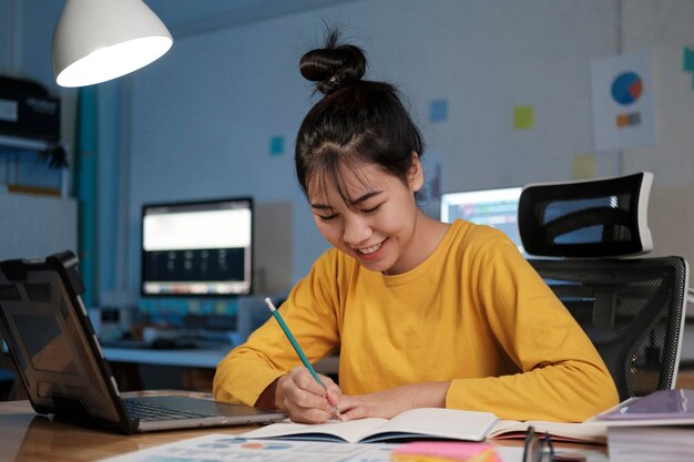 Junge asiatische Frau, die nachts im Home Office arbeitet und lernt.