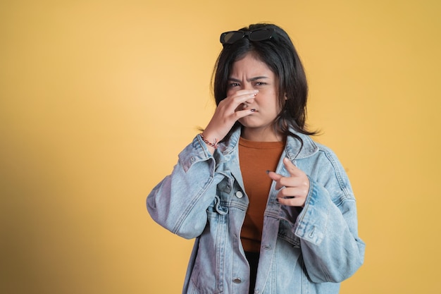 Junge asiatische frau, die nase mit finger bedeckt, wenn schlechter geruch