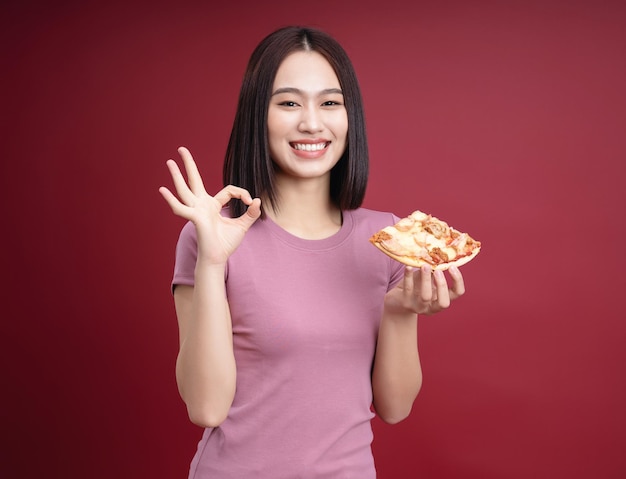 Junge asiatische Frau, die Pizza im Hintergrund isst