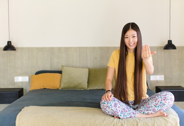 Junge asiatische Frau, die sich glücklich, erfolgreich und selbstbewusst fühlt, sich einer Herausforderung stellt und sagt, bringen Sie es auf! oder dich begrüßen