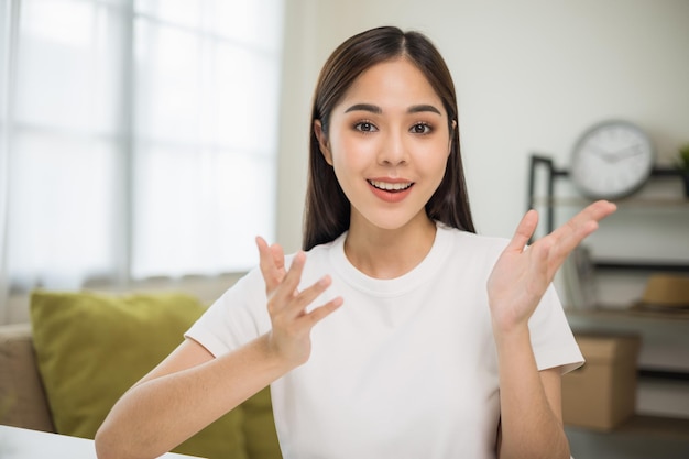 Junge asiatische frau, die sich online eine kamera-videokonferenz anschaut, die zu hause im wohnzimmer sitzt. Geschäftsfrau, die auf den Bildschirm schaut Treffen auf Social Media Live-Dampf. Arbeiten, Lernen von zu Hause aus.