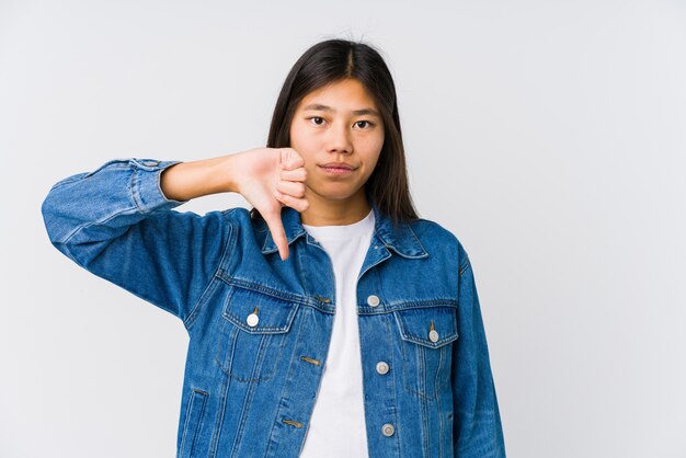 Junge asiatische Frau, die unten eine Abneigungsgeste, Daumen zeigt. Uneinigkeit Konzept.