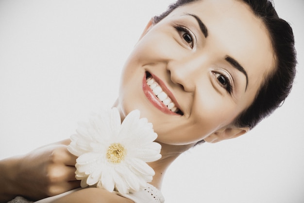 Junge asiatische Frau, die weiße gerber Blume anhält