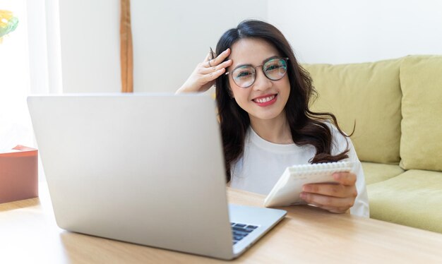 Junge asiatische Frau, die zu Hause arbeitet