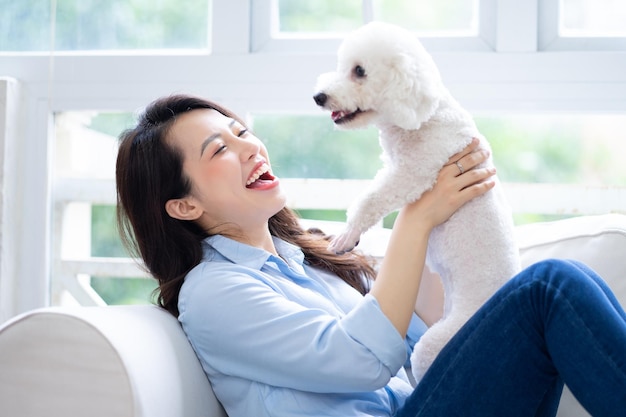 Junge asiatische Frau, die zu Hause mit Hund spielt