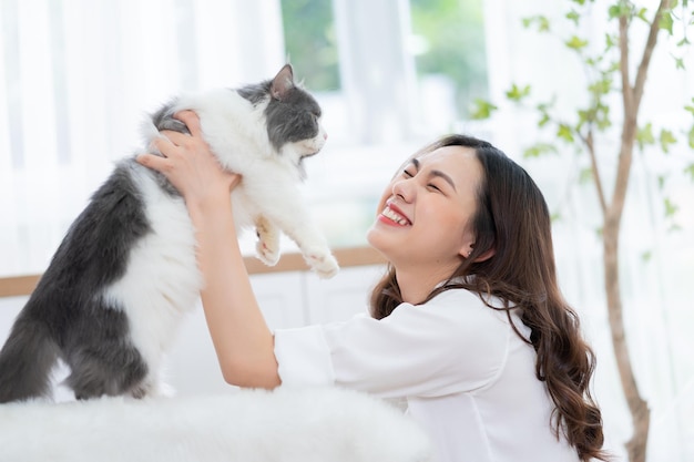 Junge asiatische Frau, die zu Hause mit Katze spielt