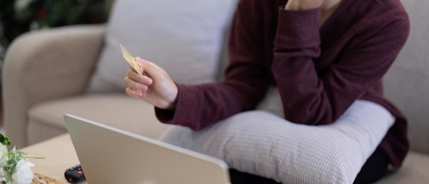 Junge asiatische Frau hält eine Kreditkarte in der Hand und benutzt einen Laptop für Internetkäufe Online-Shopping Online-Zahlung zu Hause.