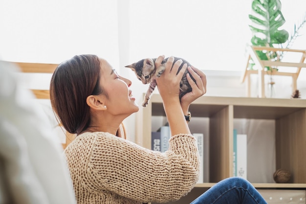 Junge asiatische Frau hält und spielt mit ihrer süßen Kätzchenkatze mit schönem Haustier- und Menschenkonzept