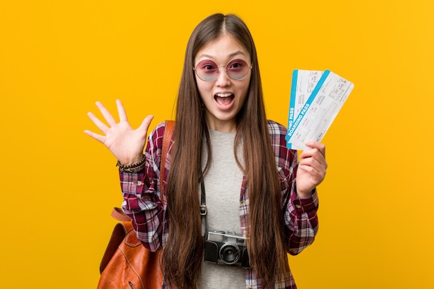 Junge asiatische Frau, halten Flugtickets, die einen Sieg feiern