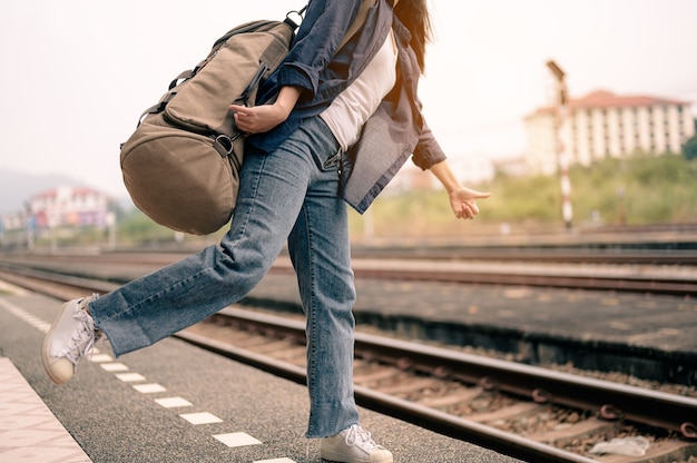 Junge asiatische Frau hebt Ihre Hand, um den Zug auf dem Bahnsteig zu winken. Konzept von Tourismus, Reisen und Erholung.