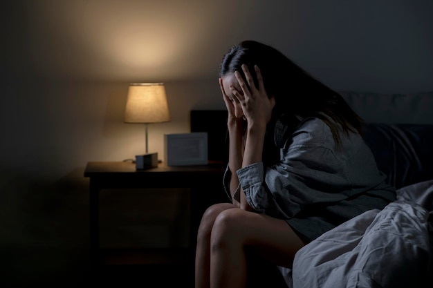 Junge asiatische Frau im Schlafzimmer, die sich traurig, müde und besorgt fühlt, leidet unter Depressionen in der psychischen Gesundheit Frau, die im Bett sitzt, kann nicht vor Schlaflosigkeit schlafen