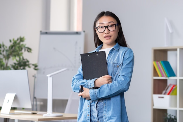 Junge asiatische Frau in Brillenpraktikantin zum ersten Mal an einem Arbeitsplatz in der Sekretärin