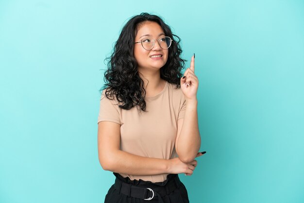 Junge asiatische Frau isoliert auf blauem Hintergrund, die eine großartige Idee zeigt