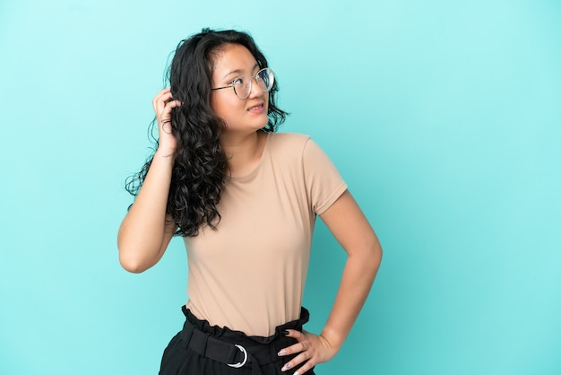 Junge asiatische Frau isoliert auf blauem Hintergrund, die eine Idee denkt