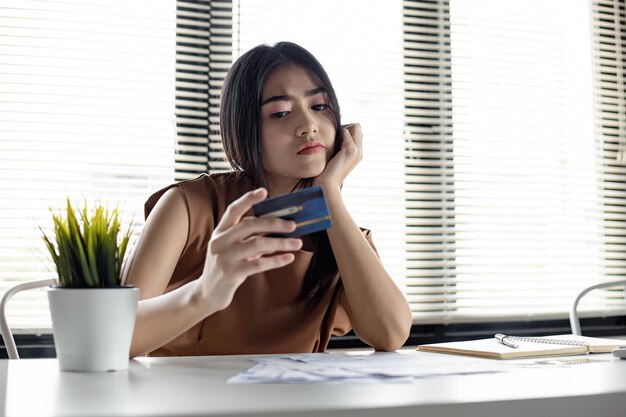 Junge asiatische Frau ist gestresst und überlegt durch Schulden von vielen Kreditkarten und Rechnungen. Konzept des finanziellen Problems. Frauen fanden einen Ausweg aus der Verschuldung zur Hand.