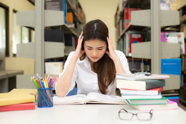 Junge asiatische Frau lesen in der modernen Bibliothek