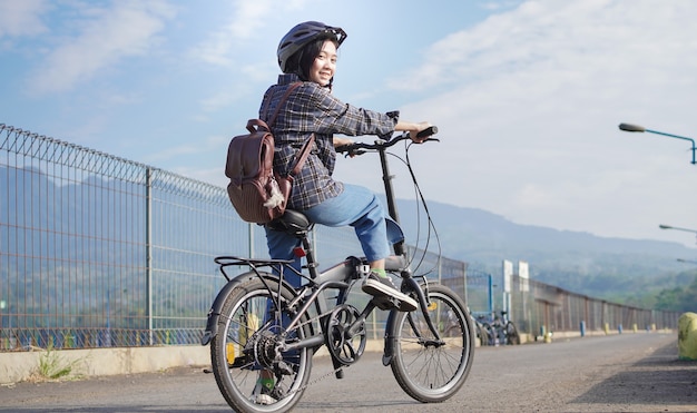 Junge asiatische Frau macht eine Pause mit dem Fahrrad, bevor sie zur Arbeit geht