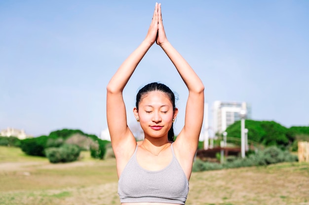 Junge asiatische Frau macht eine Yoga-Position im Park