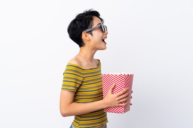 Junge asiatische Frau mit 3D-Brille und hält einen großen Eimer Popcorn