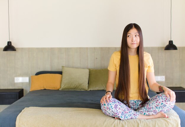 Junge asiatische Frau mit einem großen, freundlichen, sorglosen Lächeln, das positiv, entspannt und glücklich aussieht, chillend