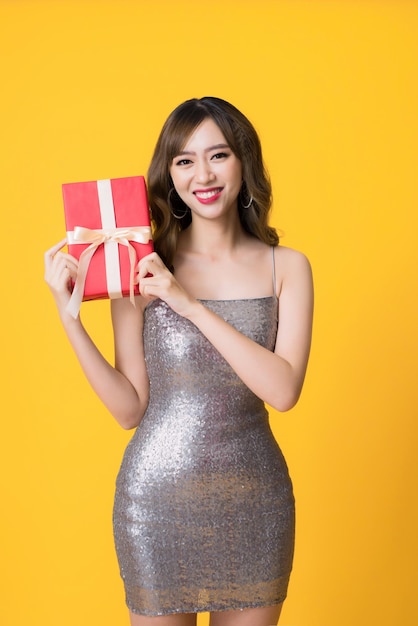 Junge asiatische Frau mit einer Geschenkbox auf gelbem Hintergrund