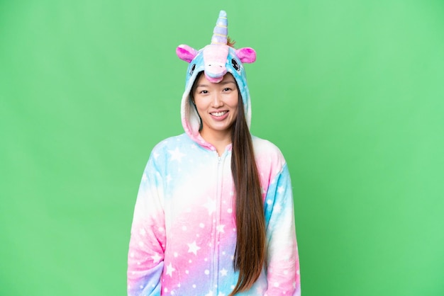 Junge asiatische Frau mit Einhorn-Pyjama vor isoliertem Chroma-Key-Hintergrund lacht