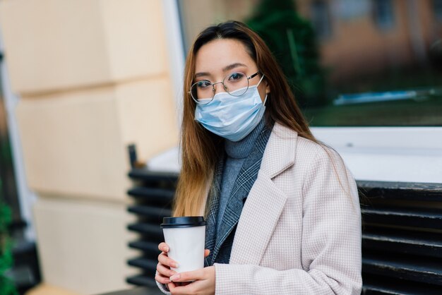 Junge asiatische frau mit gesichtsschutz der chirurgischen maske. Sie pendelt zwischen Wohnung und Arbeitsplatz in der Stadt