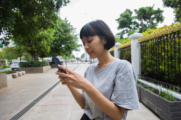 Junge asiatische Frau mit Handy im öffentlichen Raum