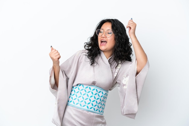Junge asiatische Frau mit Kimono isoliert auf weißem Hintergrund feiert einen Sieg