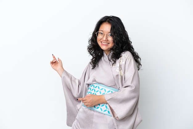 Junge asiatische Frau mit Kimono isoliert auf weißem Hintergrund macht Gitarrengeste