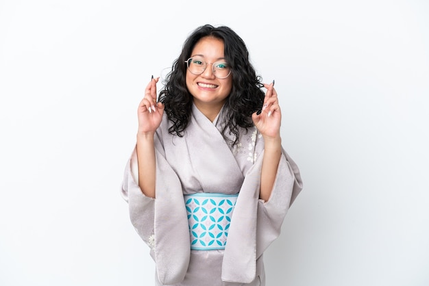 Junge asiatische frau mit kimono isoliert auf weißem hintergrund mit gekreuzten fingern