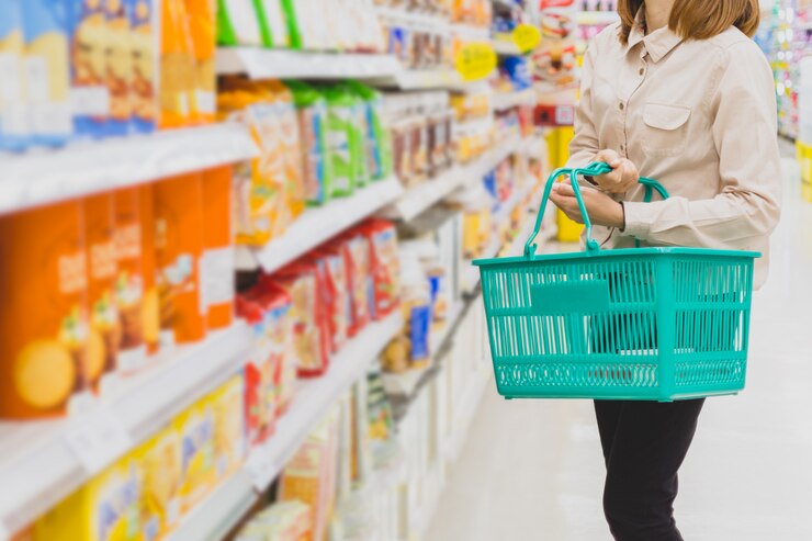 Junge asiatische Frau mit Korb am Supermarkt. Einkaufs-, Konsum- und Leutekonzept.