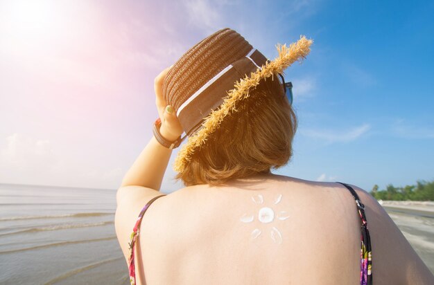 junge asiatische Frau mit Sonnencreme am Strand am sonnigen Tag