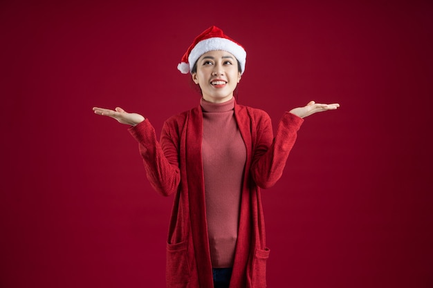 Junge asiatische Frau mit Weihnachtsmütze auf rotem Hintergrund