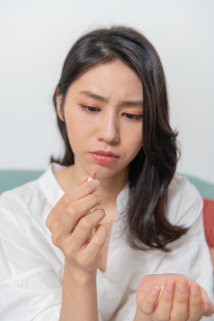 Junge asiatische Frau nimmt Medizin im Wohnzimmer ein und nimmt notwendige Medikamente sicherer ein Die Medizin steht im Fokus Menschen sind verschwommen