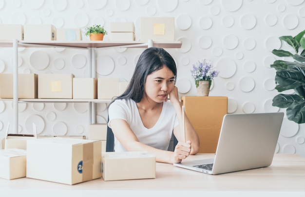 junge asiatische Frau starten Kleinunternehmer, der mit digitalem Tablet am Arbeitsplatz arbeitet.