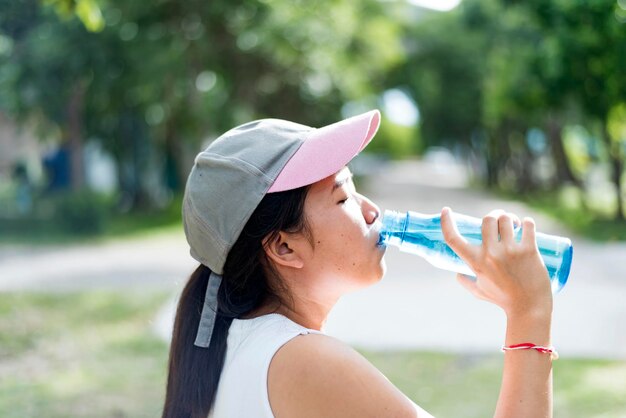 Junge asiatische Frau trinkt nach dem Joggen Wasser Gesundheits- und Sportkonzept