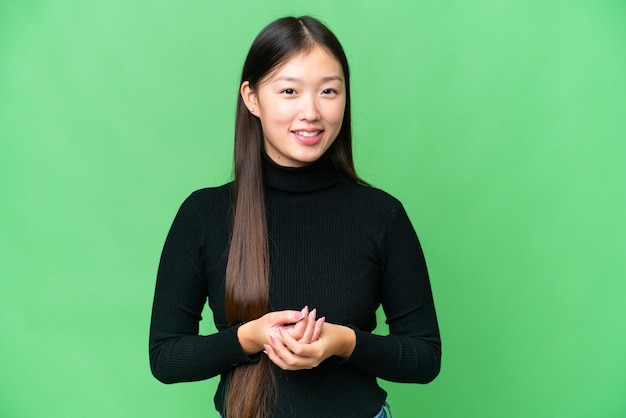 Junge asiatische Frau über isoliertem Chroma-Key-Hintergrund lachend
