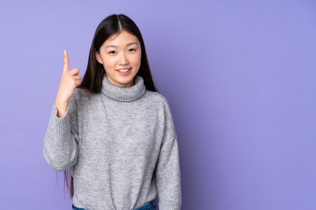 Junge asiatische Frau über Wand, die eine große Idee zeigt