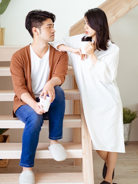 Junge asiatische Frau und Mann genießen es, Zeit zu Hause mit einer Tasse Kaffee in den Händen zu verbringen.