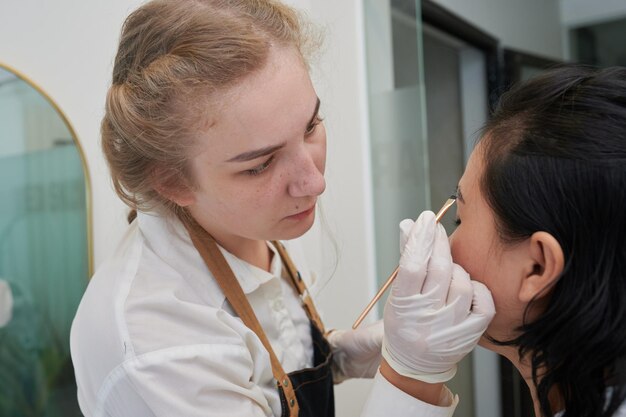 Junge asiatische Frau unterzieht sich einer Augenbrauenkorrektur im Schönheitssalon