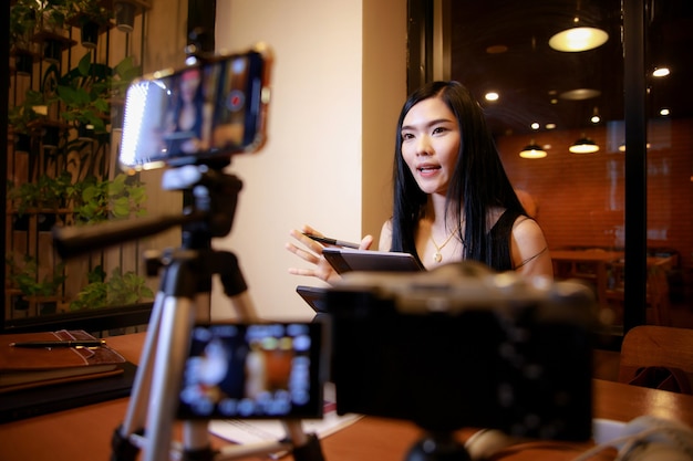 Junge asiatische Frau Vloggerin, die Videoinhalte für Online-Kanal aufnimmt, weiblich, die in die Kamera schaut und über Videoaufnahmen spricht Content Creator Maker oder Social Influencer Concept