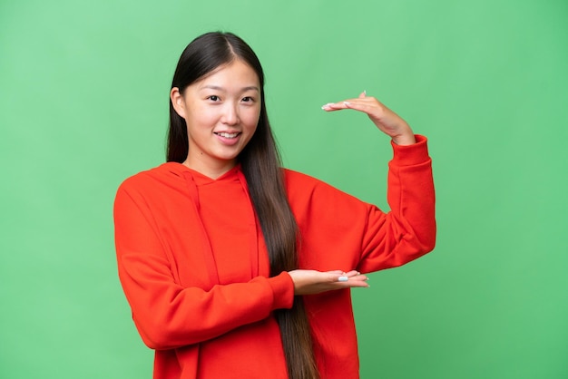 Junge asiatische Frau vor isoliertem Hintergrund, die den Mund mit der Hand bedeckt