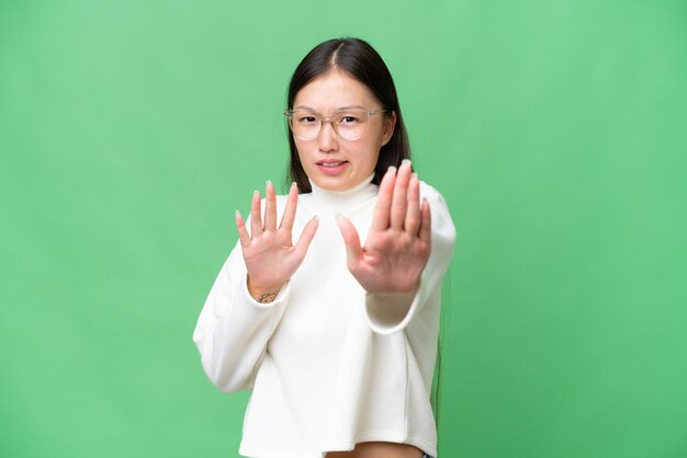 Junge asiatische Frau vor isoliertem Hintergrund, die die Hände zur Seite streckt, um zum Kommen einzuladen